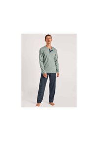 Lichtgroene blouse met lange mouwen en een notch-kraag en zak, gecombineerd met marineblauwe gestreepte pyjamabroek. Zachte stof, ontspannen pasvorm.
