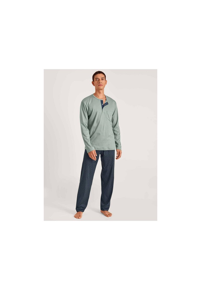 Lichtgroene blouse met lange mouwen en een notch-kraag en zak, gecombineerd met marineblauwe gestreepte pyjamabroek. Zachte stof, ontspannen pasvorm.