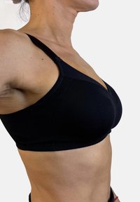 Sostén inalámbrico negro hecho de una tela suave, con escote en forma de V, tirantes ajustables y un diseño con costuras mínimas.