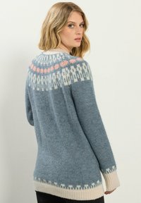 Oversized niebieski sweter wykonany z miękkiego dzianiny, z wzorzystym yoke w białym i różowym kolorze oraz kremowymi ściągaczami u dołu i na rękawach.