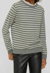 Grauer Pullover mit weißen horizontalen Streifen, geripptem Rundhalsausschnitt und Bündchen. Wird mit schwarzen Lederhosen getragen. Weiches Baumwollmaterial.