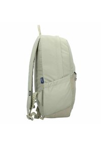 Sac à dos vert clair en tissu texturé, doté de bretelles ajustables, d'une poche latérale et d'un patch logo, avec un design épuré.