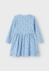 Robe longue à manches longues bleu clair avec imprimé floral, présentant une jupe froncée et des rayures verticales sur le tissu. Matière en coton doux.