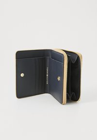 Portefeuille en cuir bleu marine avec une fermeture éclair dorée et des accents en marron. L'intérieur comprend des emplacements pour cartes et un compartiment pour les pièces de monnaie, logo imprimé à l'intérieur.