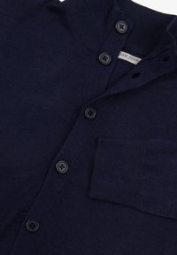 Cardigan di colore blu navy realizzato in tessuto morbido, con chiusura a bottoni, colletto a coste e taschino sul lato sinistro del petto. Sono visibili bottoni neri.