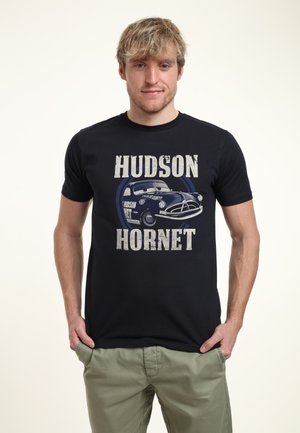 Černé tričko s potiskem vintage auta a nápisem "HUDSON HORNET" velkými, opotřebovanými bílými písmeny. Krátké rukávy, bavlněný materiál.