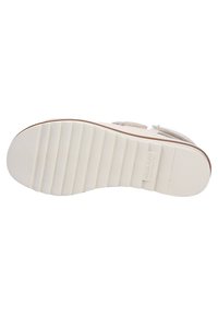 Shoe sole with a wavy tread pattern, made of rubber, in white color. Features a branded logo and smooth texture. Lightweight and flexible design.