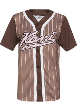 Hnědé tričko ve stylu baseball s bílými vertikálními pruhy, bílým lemem, zapínáním na knoflíky a růžovým nápisem „Kani est. 1989“ na přední straně.