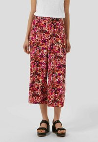 Pantalon à jambes larges avec un motif floral multicolore incluant des teintes de rose, noir et orange. Confectionné dans un tissu léger avec une coupe décontractée.