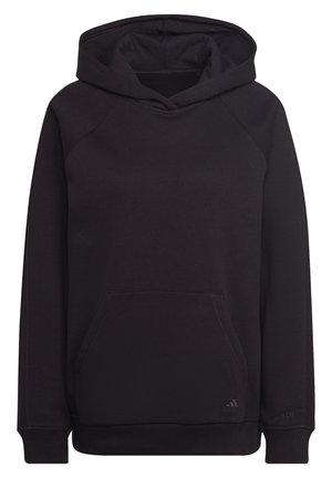 Persoon die een effen zwarte Adidas-hoodie draagt met een voorzak en geribde manchetten, getoond van schouders tot halverwege de dij tegen een witte achtergrond.