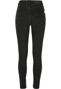 Vaqueros ajustados negros de denim, con un diseño de cintura alta, estilo de cinco bolsillos y una textura suave con detalles de costura mínimos.