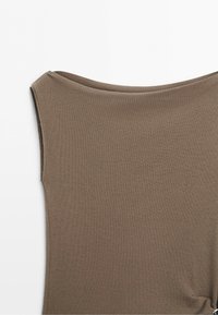 Ærmeløs brun strikketop med bred bådudskæring og glat struktur, vist på hvid baggrund.