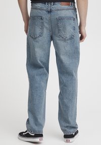 Heledad sinistusega helerohelised teksad, millel on lõdva lõikega kaks tagataskut ja nahast silt vöökohal. Viimistletud kergelt pleekinud tekstuuriga.