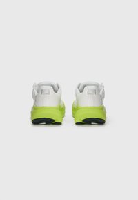 White athletic shoes with a textured upper and vibrant green sole. Features smooth heel and rounded toe with black accents on the outsole.