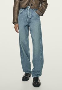 Light blue wide-leg jeans with a high waist, made of denim. Features a classic five-pocket design and subtle fading. Worn with black ankle boots.