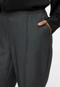 Gray, elastic-waist trousers with a slightly textured fabric. Features side pockets and a straight cut, suitable for casual or formal wear.