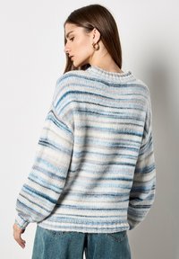 Sweter w paski w jasnoniebieskim, kremowym i szarym kolorze, o luźnym kroju, teksturowanym splocie oraz ściągaczach na mankietach i u dołu.