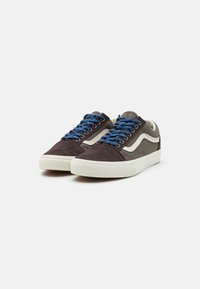 Tumedast pruuni sukapaeltega sneakersid, helesiniste aktsentidega ja siniste mustriliste paeltega. Omab valget kummist tallat ja klassikalist küljeribaga.