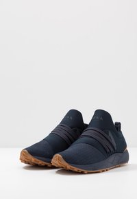 Baskets slip-on bleu marine avec un dessus texturé, des sangles élastiques et des accents perforés. Semelle extérieure en caoutchouc de couleur gomme pour une meilleure adhérence.