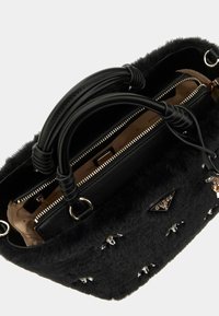Borsa nera con una texture morbida simile alla pelliccia, con accessori in oro, chiusura con zip e decorazioni sul lato esterno.