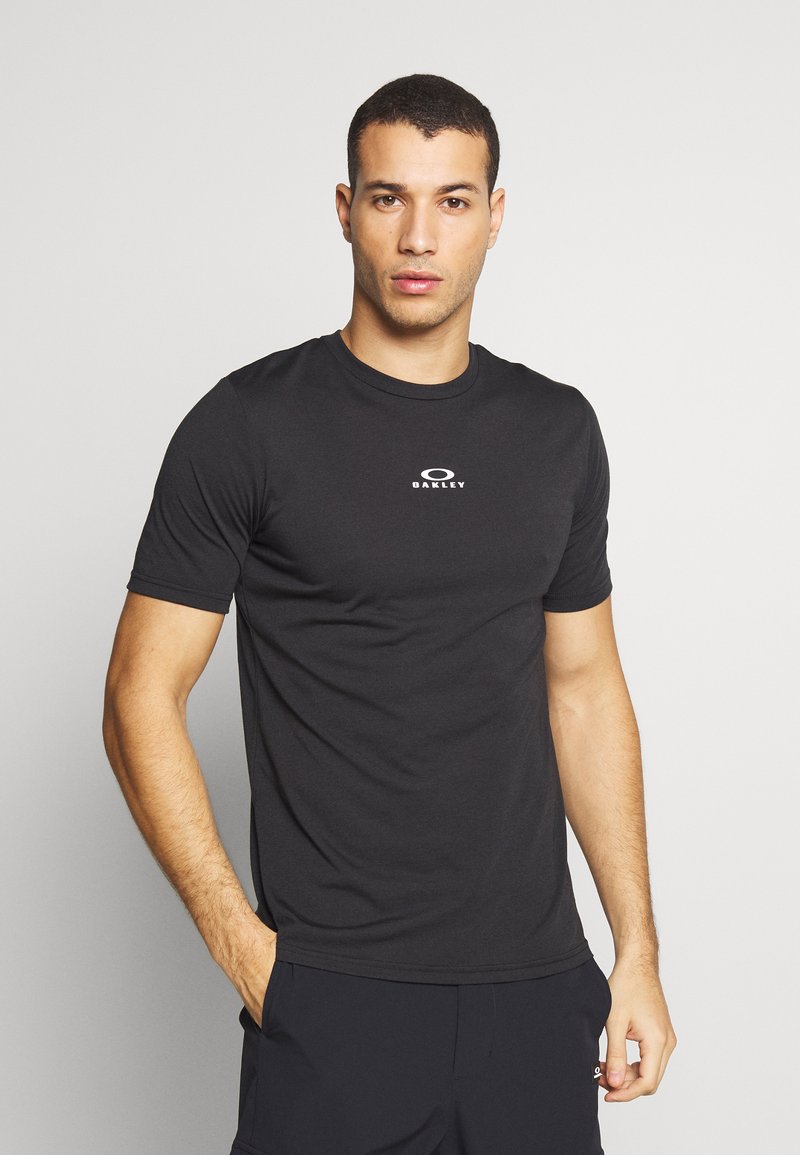 Sort kortærmet t-shirt i en tætsiddende design med et cirkulært logo på brystet og en glat, let stoftekstur.