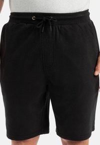 Bermudas de algodón negras con una cinturilla elástica, detalle de cordón y bolsillos laterales, con una textura suave y un ajuste relajado.