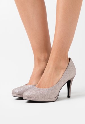 Escarpins à talons aiguilles en rose doré pailleté avec bout rond et design épuré, présentant une texture lisse et un talon stiletto noir.