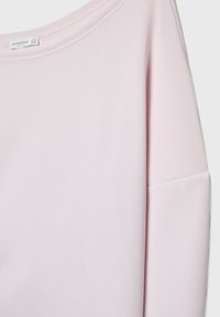 Hellrosa langärmliges Oberteil mit weitem Ausschnitt, aus weichem Material gefertigt. Es hat eine lockere Passform und einen abgesenkten Schulternaht.