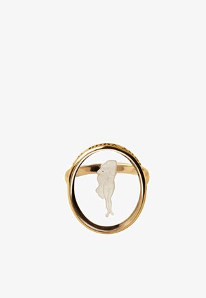 Anillo de oro con una cara circular transparente que presenta la silueta blanca de una mujer cubriendo su pecho con un brazo.