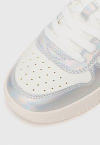 Adidași albi cu accente iridescente, perforații și piele texturată. Include șireturi albe plate și o talpă din cauciuc de culoare deschisă.