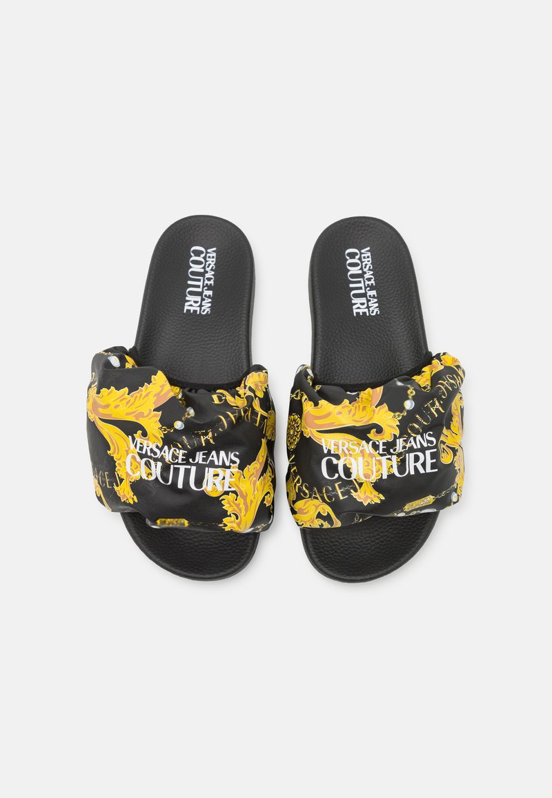Czarne klapki z wyściełanym paskiem z złotym drukiem barokowym i logo, teksturowana podeszwa dla lepszej przyczepności.