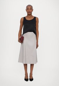 Black sleeveless top, light gray A-line skirt, and black pointed-toe heels. Holding a small burgundy clutch with silver accents.