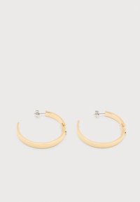 Σκουλαρίκια μισή κύκλου σε χρυσό τόνο με υφή, με καρφίτσα και πεταλούδα κούμπωμα, σε απλή λευκή επιφάνεια.