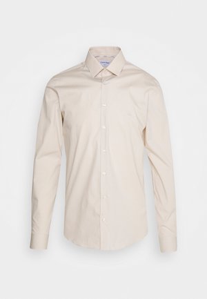 Beige-langarm-Hemdbluse mit Knopfleiste und spitzem Kragen, dezentem "ck"-Logo auf der Brust und knöpfbaren Manschetten.