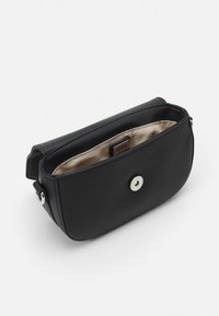 Svart läderaxelväska med en slät yta, knappstängning och beige tygfoder. Kompakt rektangulär form med rundade kanter.