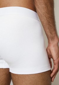 Boxer shorts bianchi con costine e cintura liscia, caratterizzati da una vestibilità aderente e una superficie morbida. Il tessuto appare leggero e elastico.