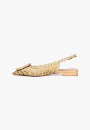 Zapato plano beige tejido con puntera puntiaguda, detalle de hebilla circular y tacón bajo apilado.