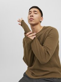 Brązowy sweter o teksturowanej powierzchni z długimi, dopasowanymi rękawami. Materiał ma wzór w wafle. Prosty fason z luźnym krojem.