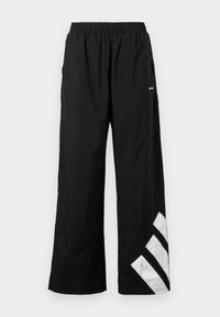 Schwarze Hosen mit weitem Bein aus leichtem Material, mit elastischem Bund und einem weißen diagonalen Streifendesign am linken Bein.