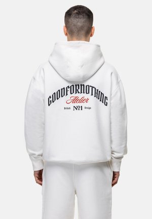 Witte hoodie met een grote zwart- en rode grafische tekst op de achterkant. Zacht materiaal, losse pasvorm en een capuchon met ribgebreide manchetten. Gecombineerd met bijpassende broek.