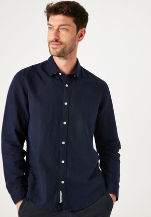 Navy blue long-sleeve shirt made of textured fabric, featuring a button-down collar and contrasting white buttons along the front.