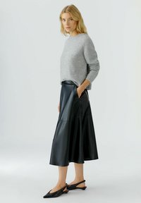 Grijze gebreide trui, zwarte leren midi-rok met zakken en zwarte slingback schoenen. Eenvoudig ontwerp en gladde texturen.