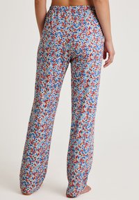 Bloem bedrukte wijde broek met een witte basis, met rode en blauwe bloemen. Gemaakt van zachte stof met een elastische tailleband.
