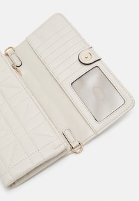 Beige quiltet pung inderside med kortslot, gennemsigtig ID-lomme og guld hardware accenter. Lynlåslomme til sikker opbevaring.