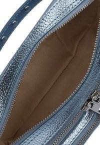 Metallisch blauwe handtas met een gestructureerd oppervlak, ritsafsluiting en een beige stoffen interieur. Inclusief een afneembare schouderband en zilveren hardware.