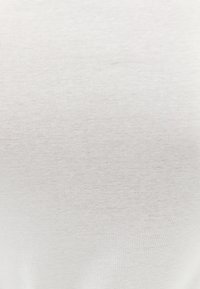 Vitt bomullstyg med en slät, något texturerad yta. Materialet verkar lätt och elastiskt, utan synliga mönster eller utsmyckningar.