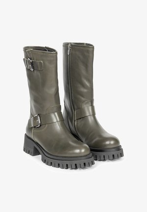 Oliwkowe skórzane, sięgające kolan botki z masywną czarną gumową podeszwą, z bocznym zamkiem błyskawicznym i regulowanym paskiem z detalem klamry.