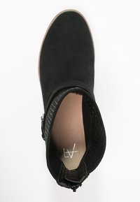 Czarne zamszowe botki za kostkę z okrągłym noskiem, perforowanymi detalami przy kołnierzu i niskim, tłoczonym obcasem. Zamek błyskawiczny z boku ułatwiający zakładanie.