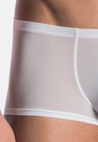 White men's boxer shorts made from a smooth, stretchy fabric. They feature a soft waistband and a fitted design that outlines the body shape.