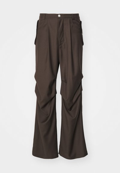 Rjave krojene hlače širokega kroja, s stranskimi žepi in sprednjim gumbom. Gladek material z rahlimi pregibi.